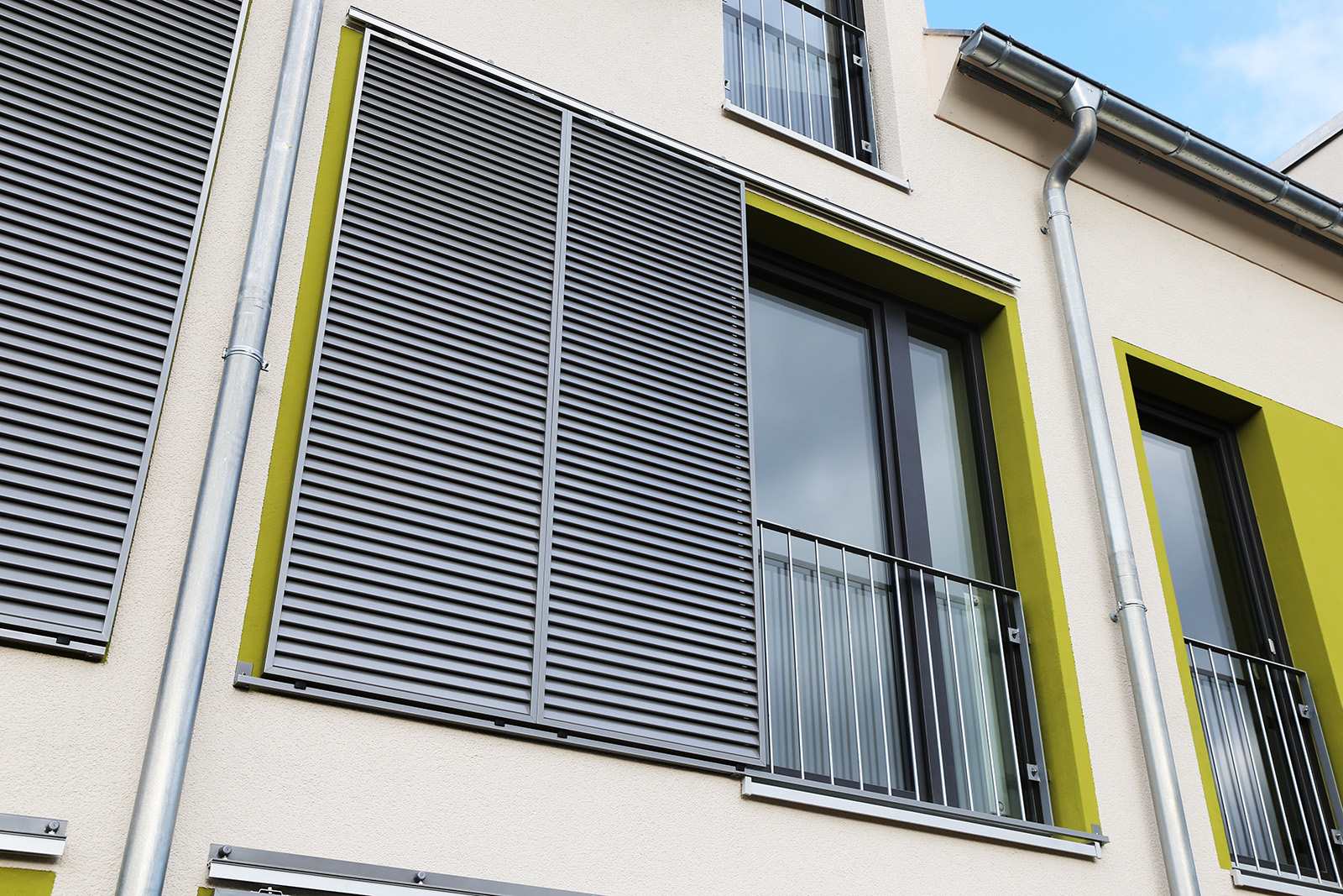 Graue Lamellen-Schiebeläden an moderner Fassade