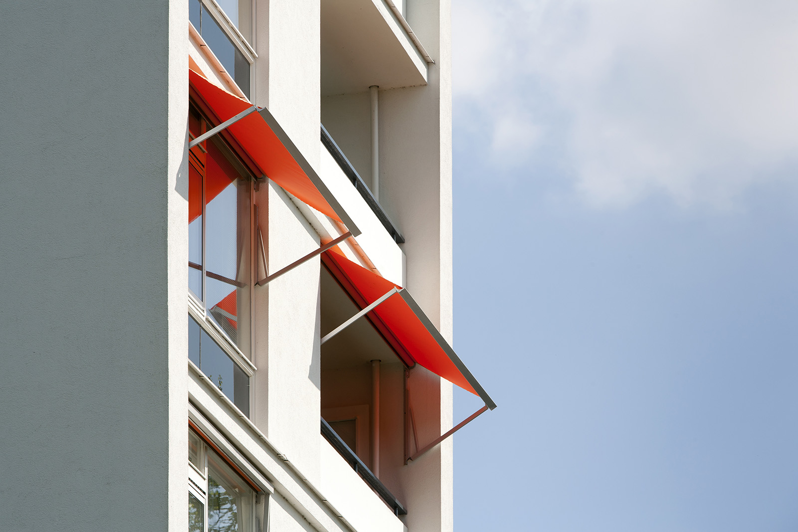 Orangefarbene Fallarm-Fenstermarkisen an einer Fassade